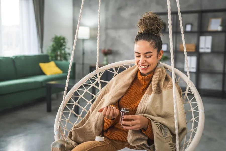 A woman is sitting on a chair taking a supplement